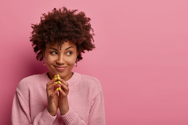 Free photo sly smiling woman has artful plan, has intention to prepare pleasant surprise