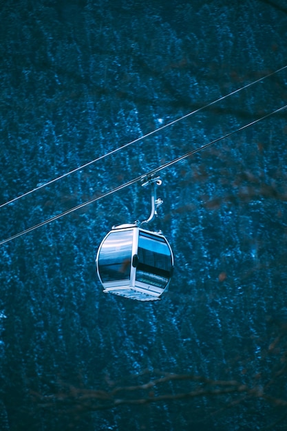 Small aerial ski lift moves fast on cableway from downtown to ski slopes in winter resort