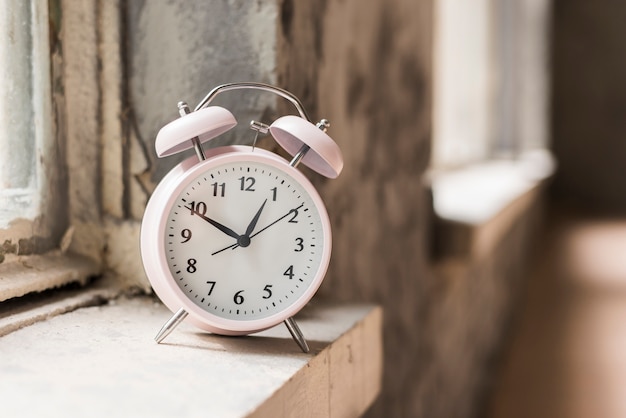 Small alarm clock on wooden sill near the window