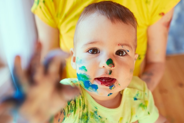 The small baby has paint on his face