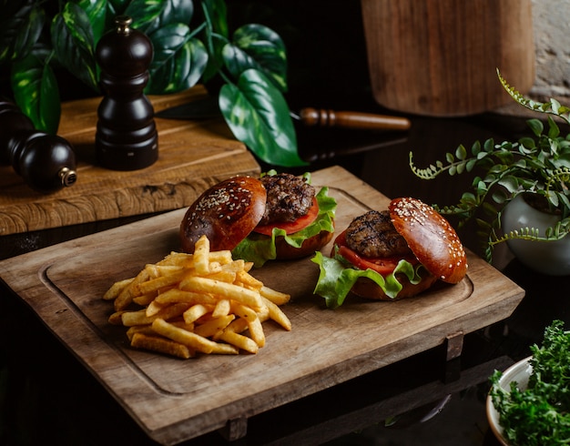 Small beef burgers without cheese on wooden board.