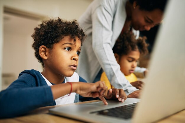 Маленький черный мальчик учится на компьютере дома
