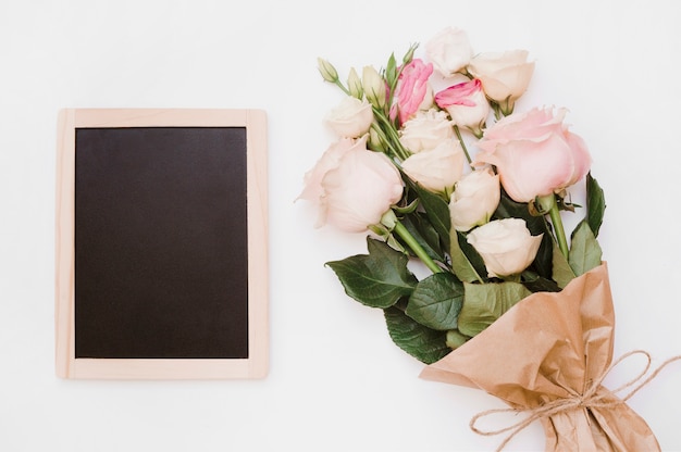 Small blank wooden slate with flower bouquet on white background