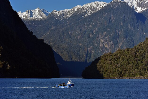 Small boat in the lake surrounded with dense forests