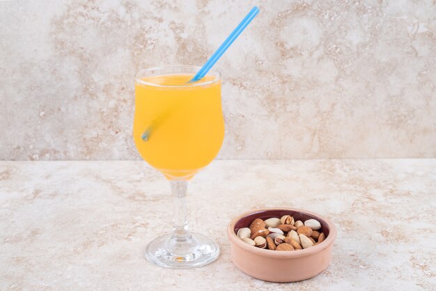 A small bowl of almonds and pistachios and a glass of juice 