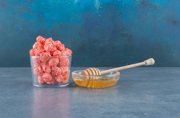 팝콘 사탕의 작은 그릇과 파란색에 꿀 숟가락으로 꿀 서빙