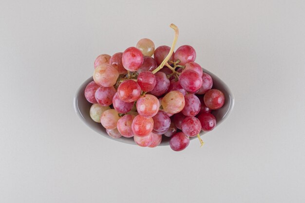 Маленькая чаша с виноградной гроздью на мраморе
