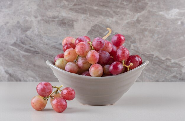 Small bowl with a grape cluster on marble 