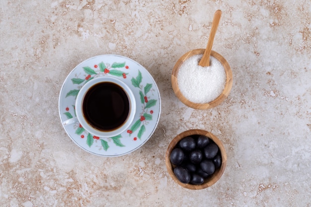 Small bowls of sugar and candies next to a cup of coffee 