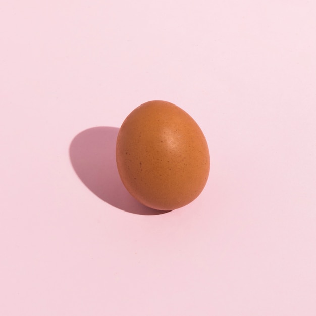 Small brown chicken egg on pink table