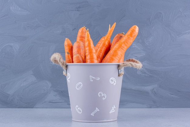 Foto gratuita piccolo secchio di carote su sfondo marmo.