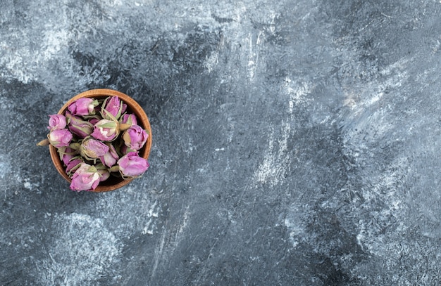 Piccole rose in boccio in ciotola di legno.