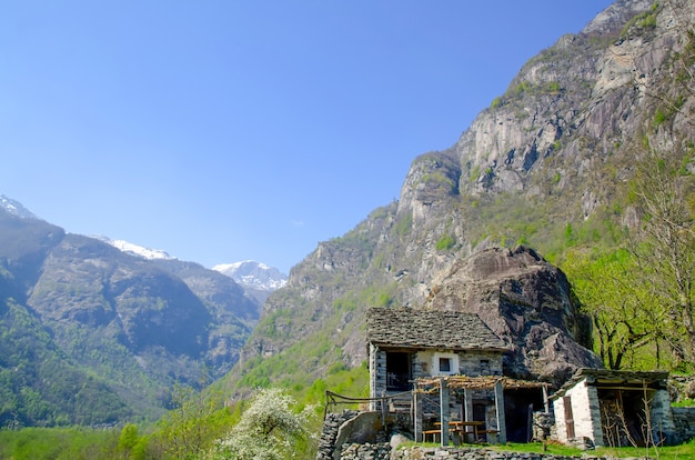 스위스 티치노의 녹지로 덮인 바위로 둘러싸인 산에 작은 건물