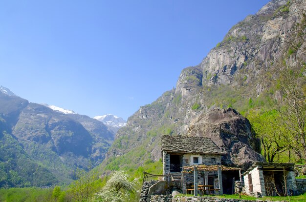 Small building on the mountain surrounded by rocks covered in greenery in Ticino in Switzerland