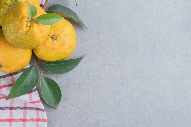 A small bundle of tangerines on a towel on marble . 