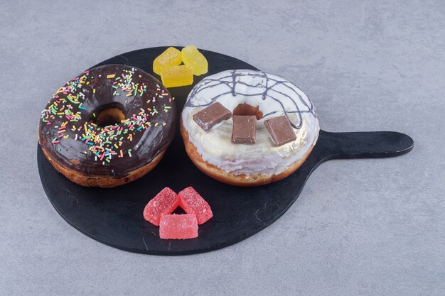 대리석 표면의 쟁반에 작은 마멜 레이드 묶음과 두 개의 도넛