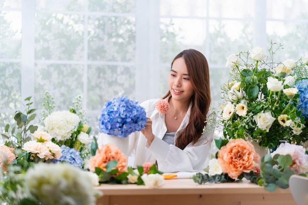 소기업 아시아 여성 꽃집 미소 꽃집에서 꽃꽂이 꽃 디자인 가게 행복 미소 재택 사업에서 꽃 작업을 준비하는 고객을 위해 꽃병을 만드는 젊은 아가씨