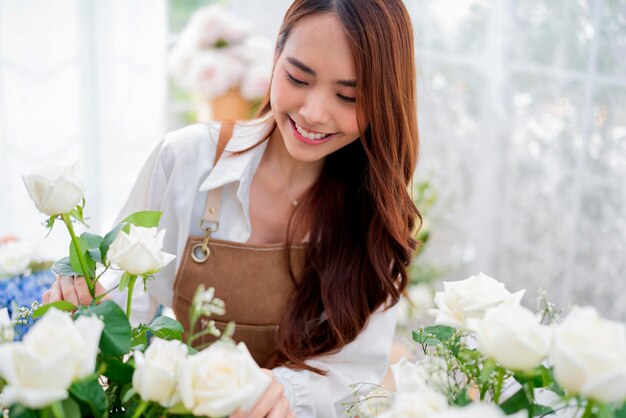 Small business Asia Female florist smile arranging flowers in floral shop Flower design store happiness smiling young lady making flower vase for customers preparing flower work from home business