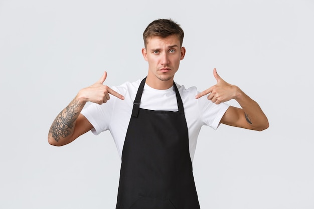Free photo small business owners, coffee shop and staff concept. handsome and confident barista show-off, looking cool and pointing at himself, bragging waiter experience and skill, white background