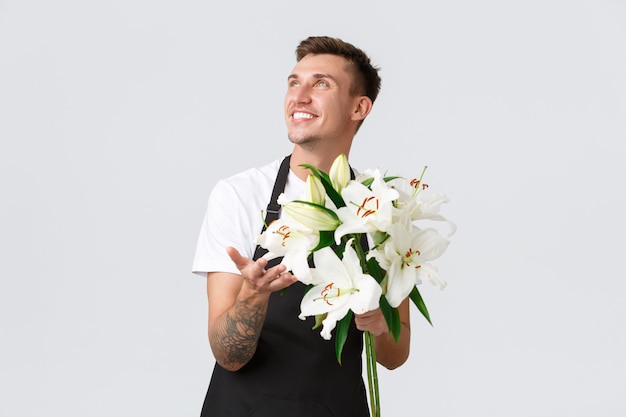 Small business retail and employees concept charismatic happy salesman florist in flower shop making...