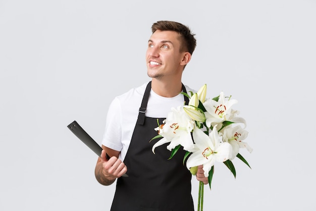 Small business retail and employees concept handsome salesman delivery guy from flower shop holding ...