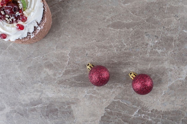 A small cake and christmas baubles on marble surface