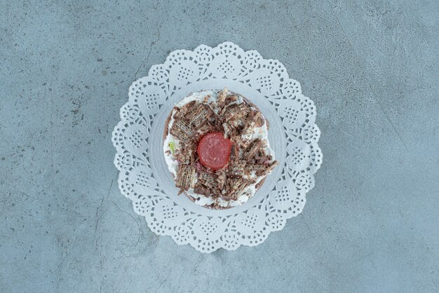 A small cake on a doily on marble background. High quality photo