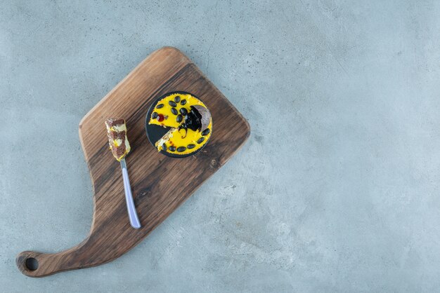 A small cake and a fork on a wooden board on marble background. High quality photo