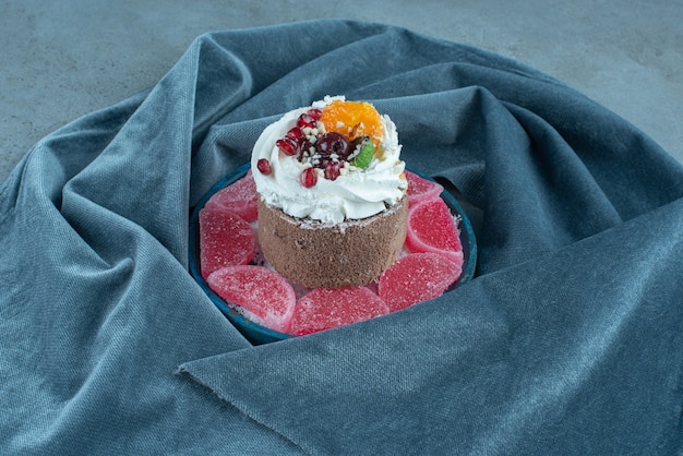 Small cake and marmelades on a platter on marble.