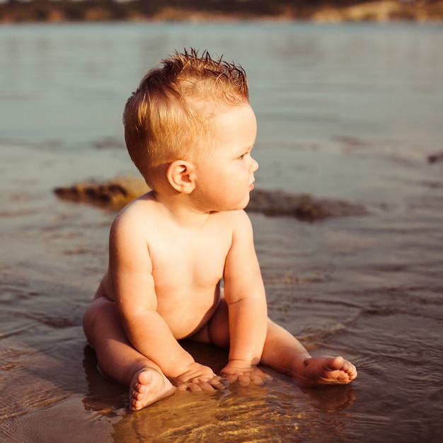 Il piccolo bambino si siede nell'acqua