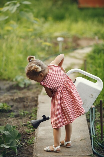Маленький ребенок из лейки с цветами поливает. Девушка с воронкой. Ребенок в розовом платье.