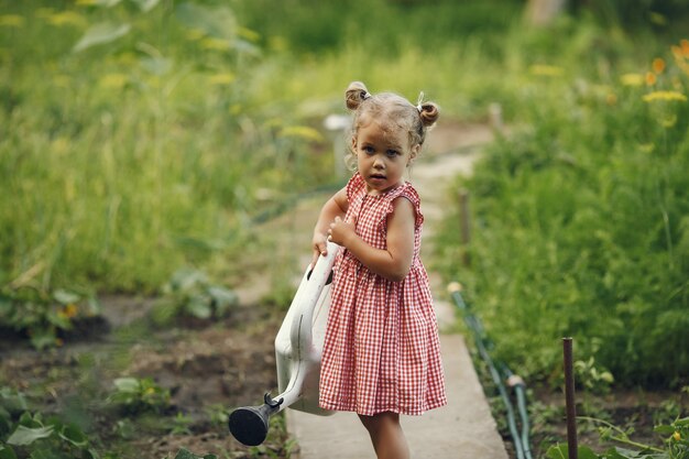 Маленький ребенок из лейки с цветами поливает. Девушка с воронкой. Ребенок в розовом платье.