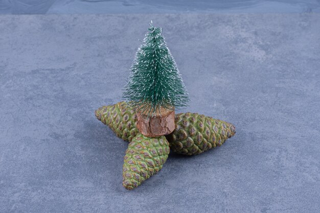 A small Christmas tree with pinecones on a gray surface