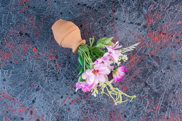 A small clay bowl with bouquet of flowers on marble background.