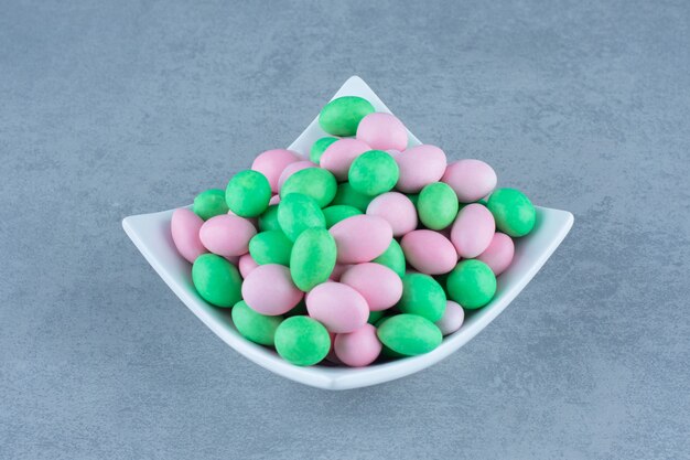 Small colorful chocolate in the bowl, on the marble table. 