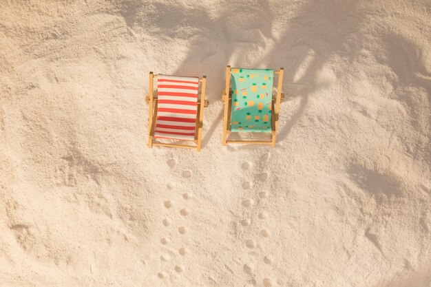 Small colorful deckchairs and footprints on sand