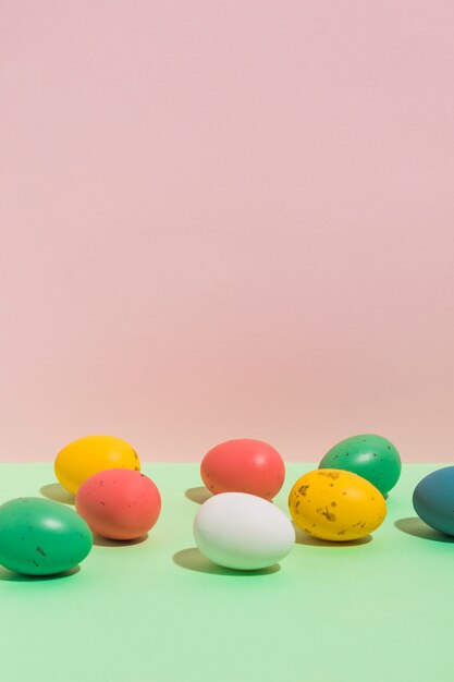 Маленькие красочные пасхальные яйца разбросаны по яркому столу