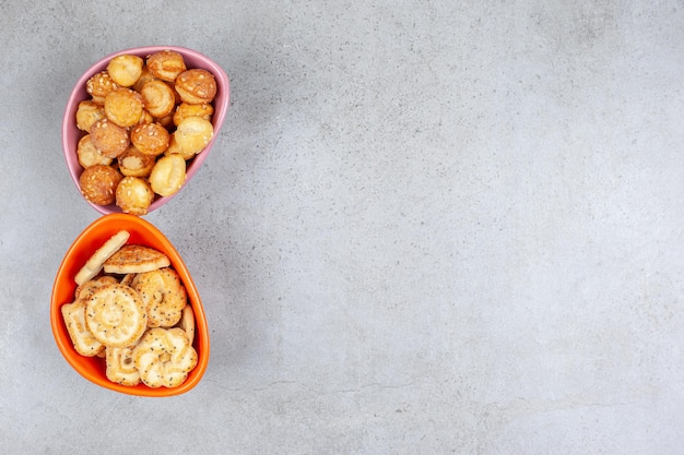 Small cookies piled in two bowls on marble surface