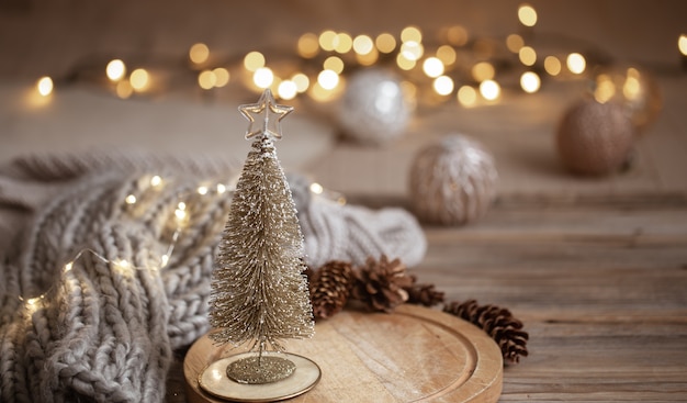 Free photo small decorative shiny christmas tree close up on a background of blurry lights with bokeh in warm colors.