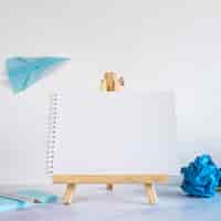 Free photo small easel with paper airplane on desk