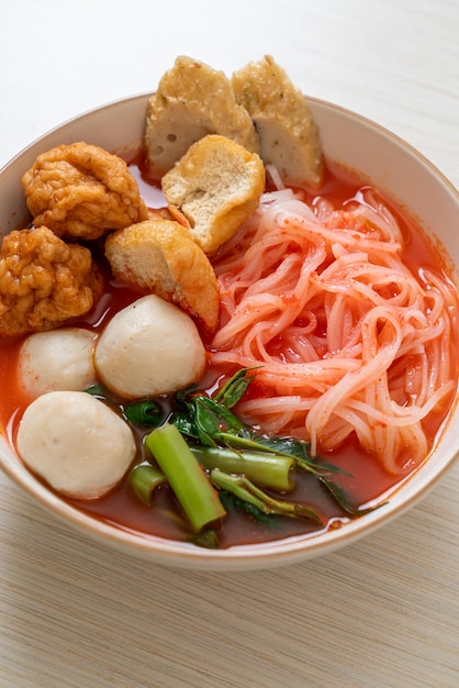 ピンクのスープ、イェンタフォーまたはイェンタフォのフィッシュボールとエビのボールが付いた小さな平らなライスヌードル-アジア料理スタイル Premium写真