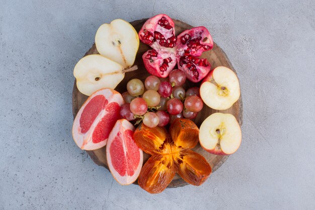 A small fruit assortment on a wooden board on marble background. 