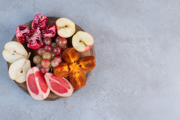 A small fruit assortment on a wooden board on marble background. 