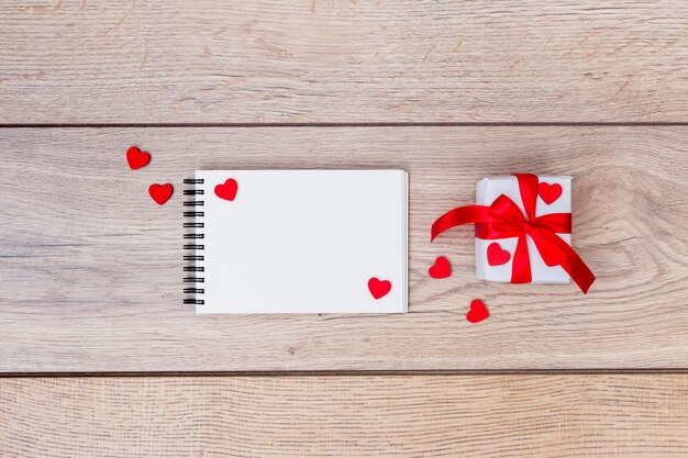 Small gift box with notepad and hearts on table 