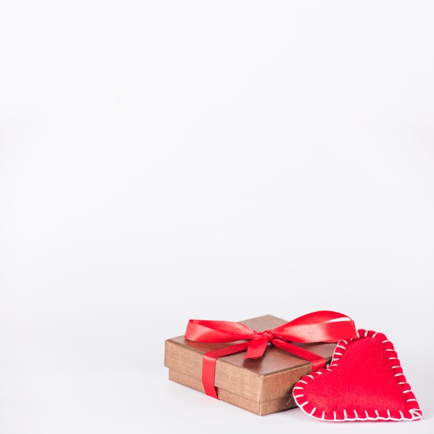 Small gift box with toy heart on table 