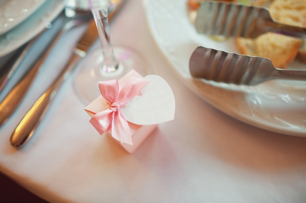 "Small gift bundled on table among dishware"