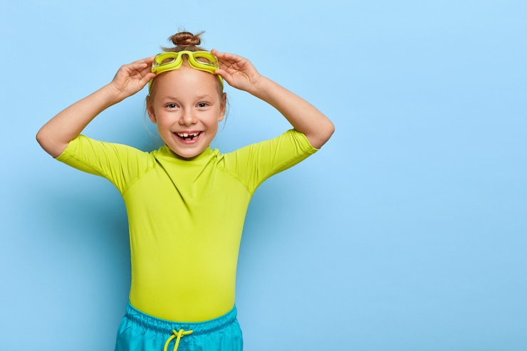 Free Photo small girl adjusts goggles, prepares for floating in pool