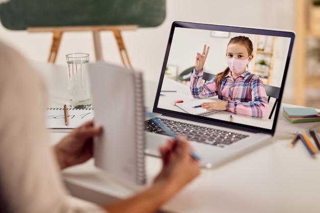 Free photo small girl answering teacher's questing while having online class during coronavirus epidemic