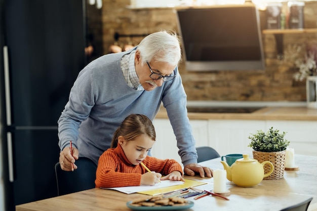Foto gratuita bambina e suo nonno che disegnano sulla carta a casa