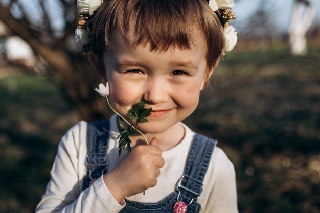 The small girl sniffs a flower